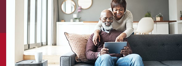 couple on couch look at tablet