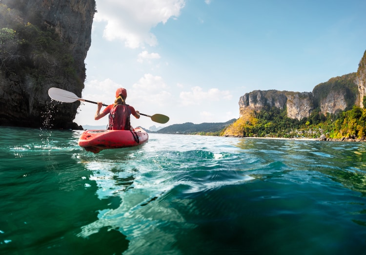 Person kayaking in river with canyon wall in distance