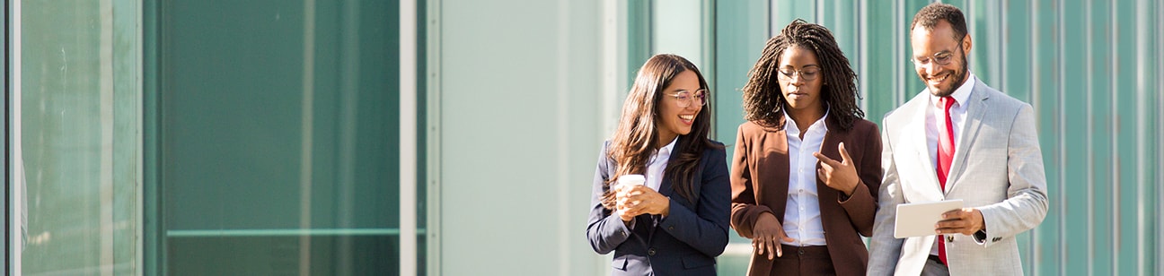 3 co-workers walk across walkway outside office building