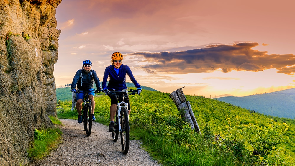Couple rides bikes on hillside trail
