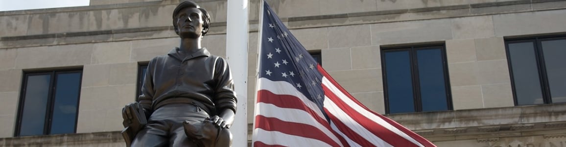 American flag flies next to statue of young Abe Lincoln