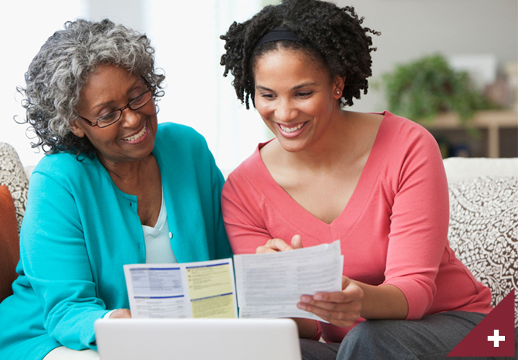 Woman sits with mother and both smile as they go through documents