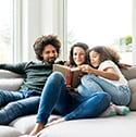 family sits on couch while looking at book