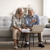 couple sits on couch and looks at laptop