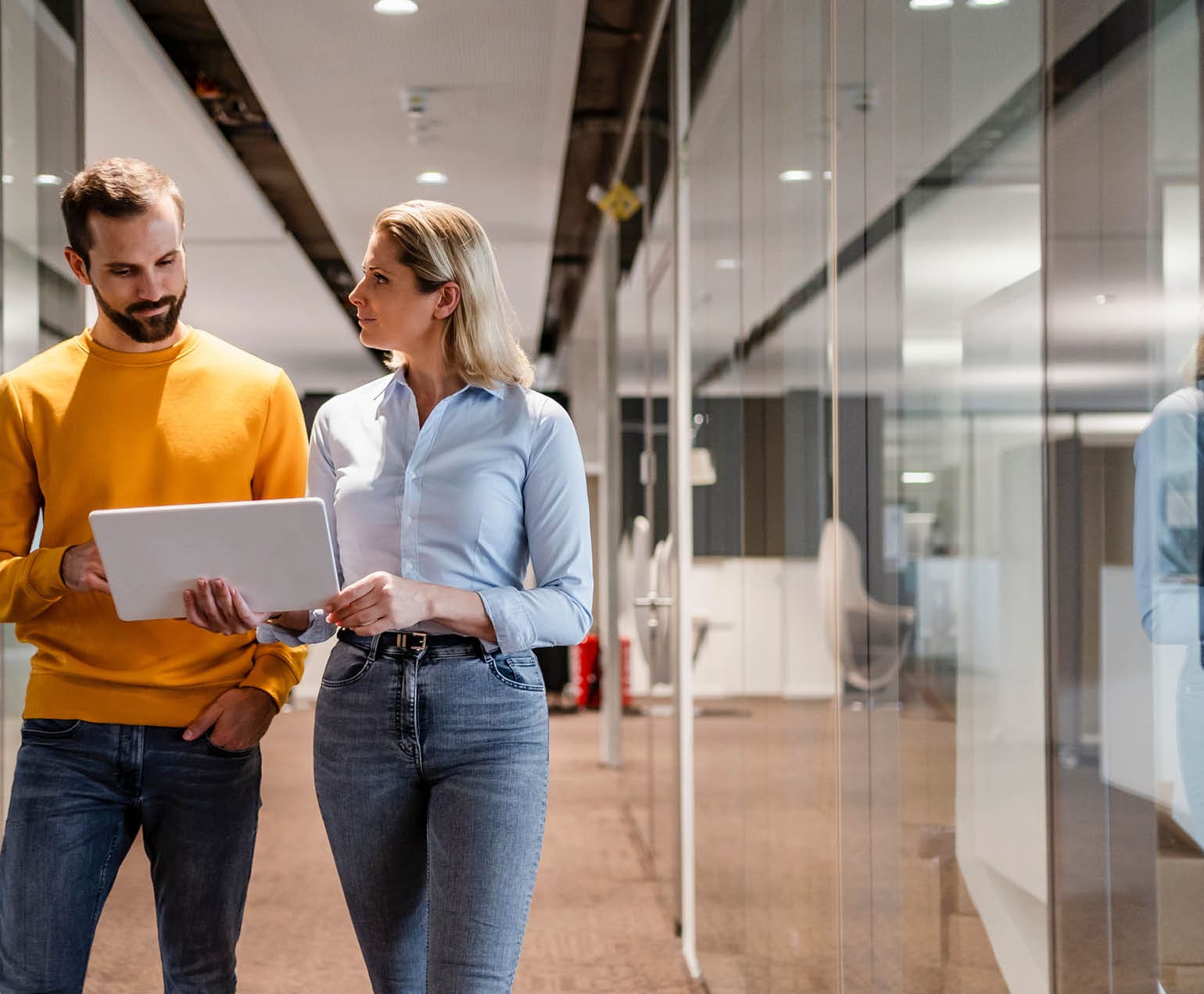 coworkers walking down a hall looking at a laptop