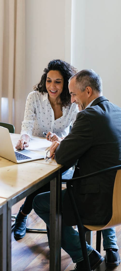 A woman and man reviewing document on computer at table