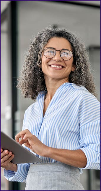 Smiling mature professional business woman bank manager, older happy female executive or lady entrepreneur holding digital tablet pad standing in office at work, looking away at copy space.