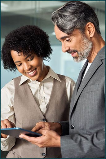 Two busy happy diverse professional business team people working in office with digital tablet. Male executive manager talking to female colleague having conversation standing at work. Vertical photo.