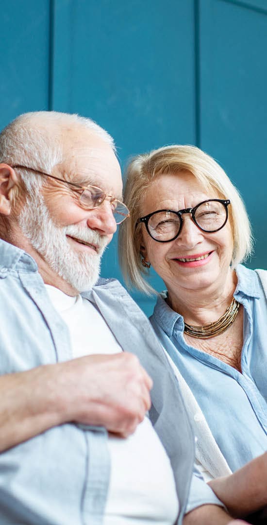 Image of an older couple looking at a tablet together, smiling.