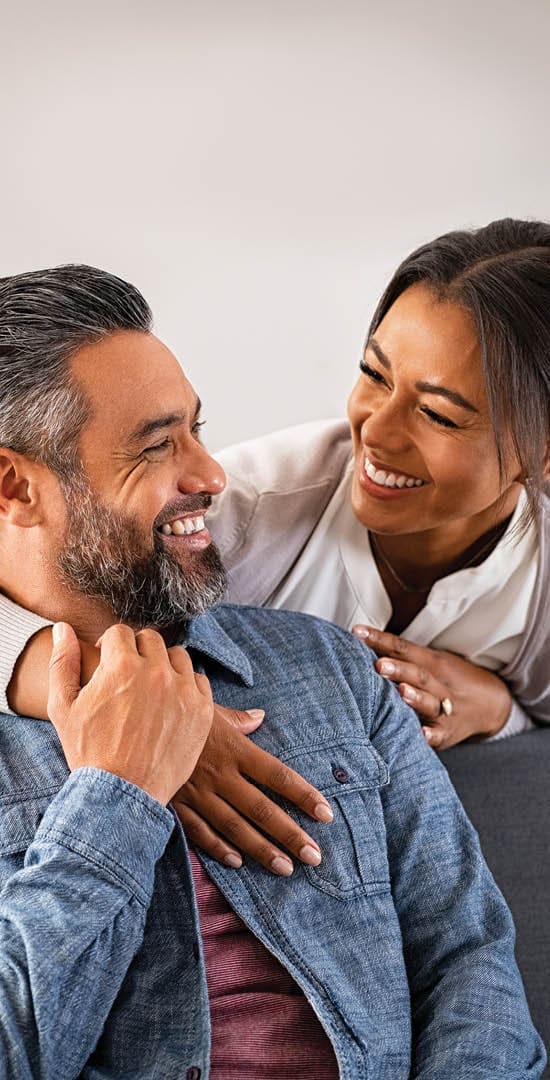 Image of younger couple laughing and embracing.