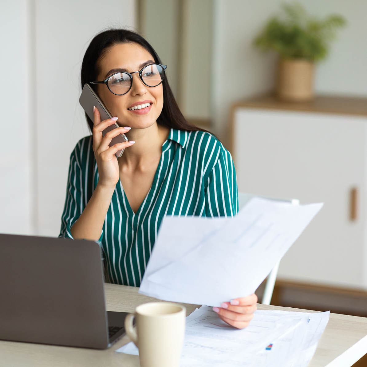 woman on phone working at laptop