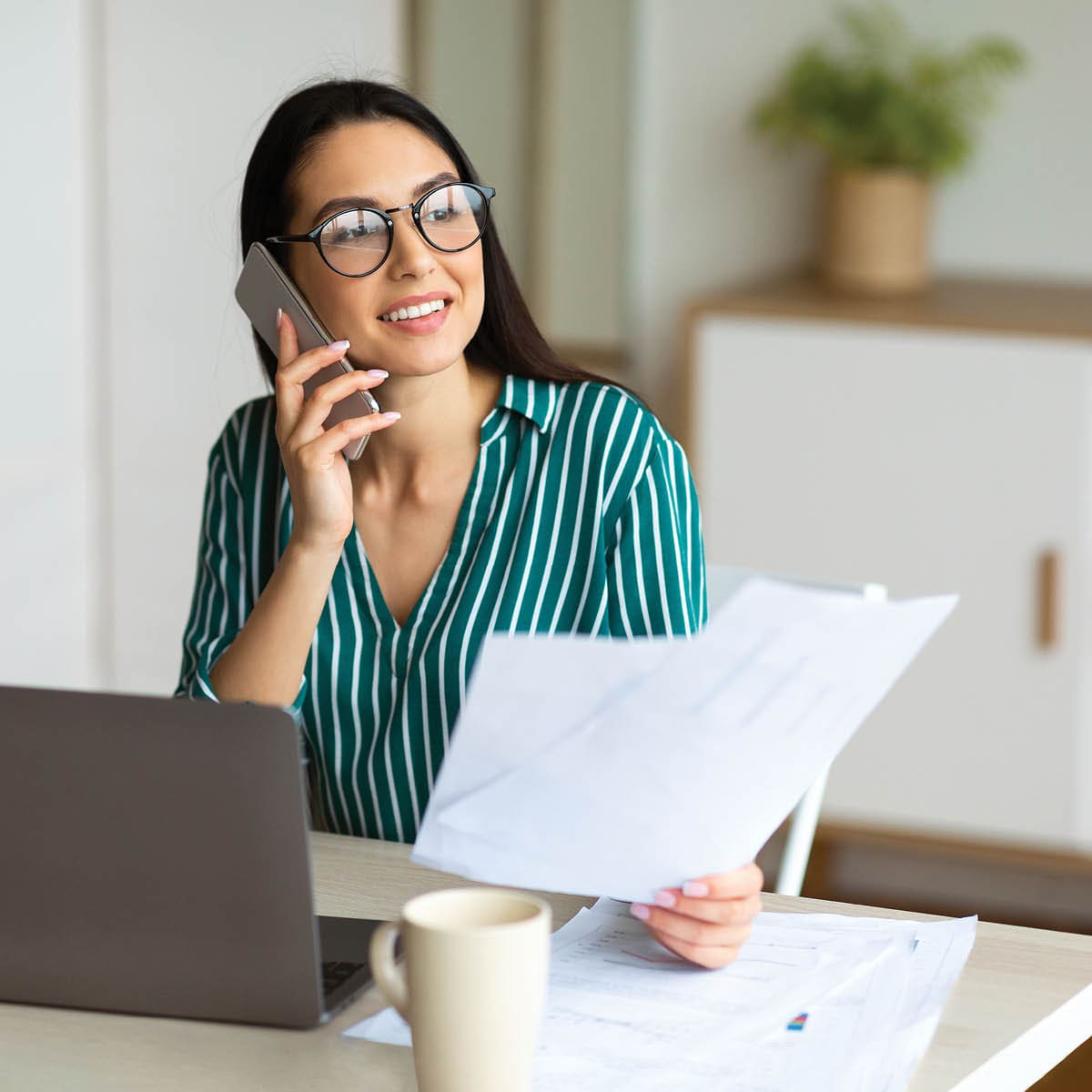 woman on phone working at laptop