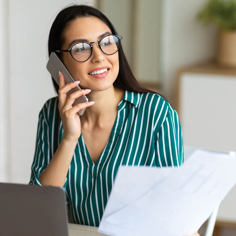 woman on phone working at laptop