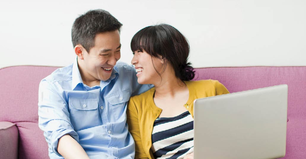 couple looking at laptop on while sitting on a couch