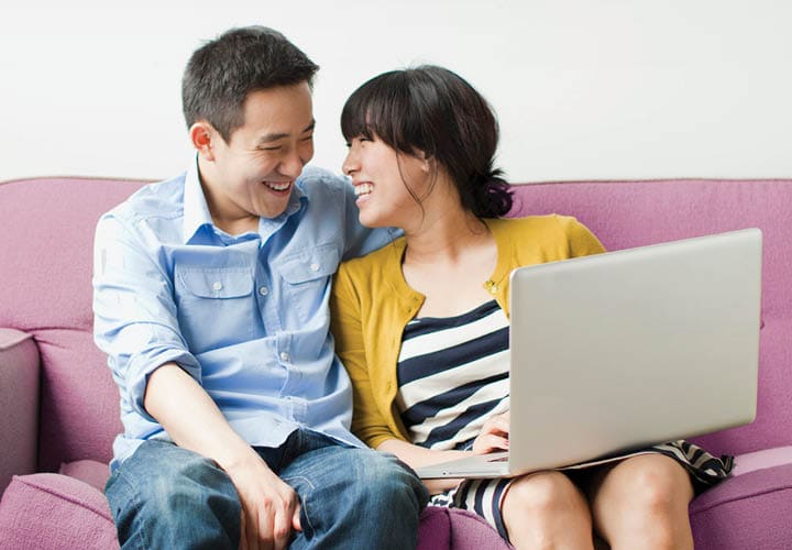 couple looking at laptop on while sitting on a couch